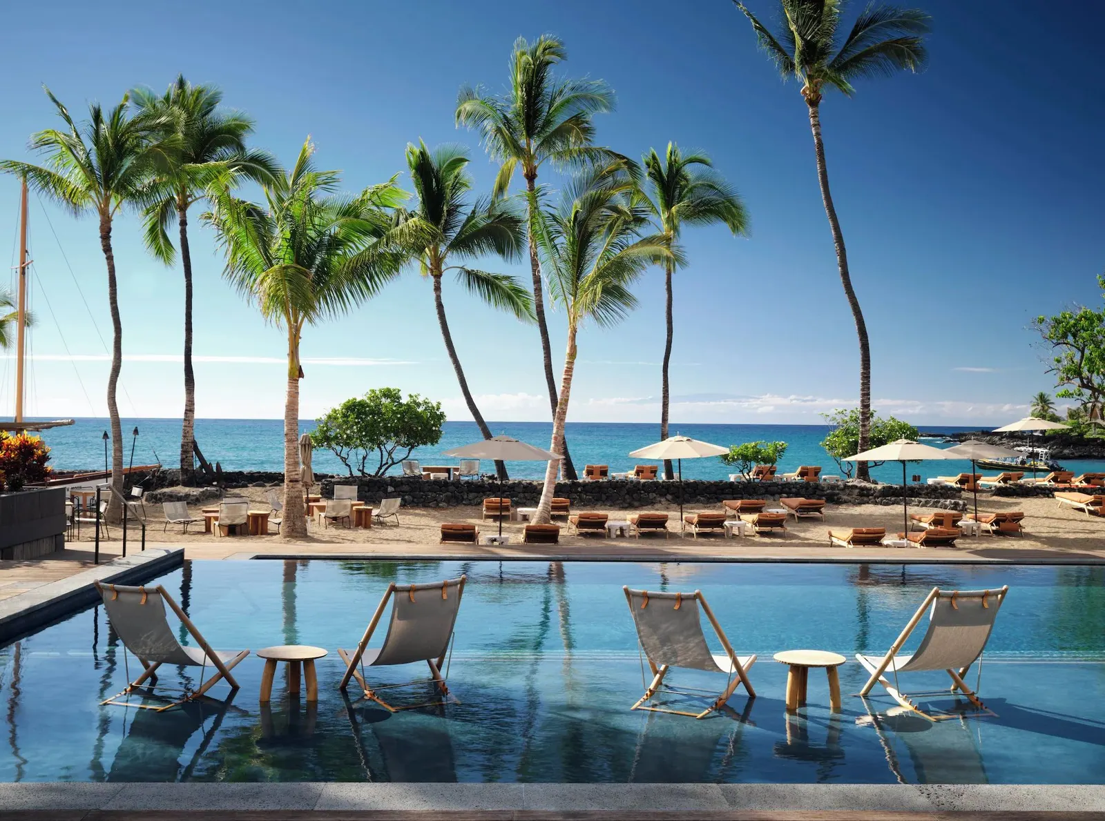Resort pool and beach framed by palm trees on the Hawaii coast