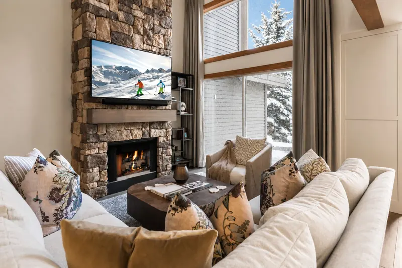 Park City residence living room with a stone fireplace and snowy window views
